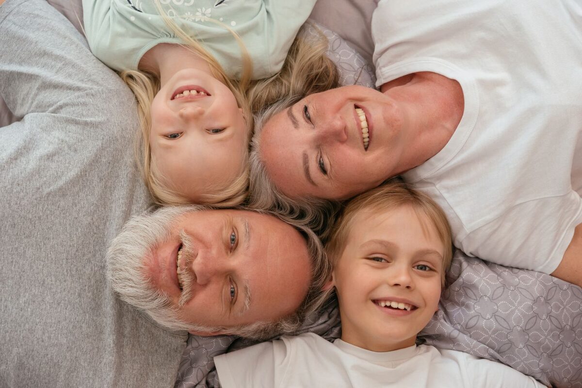 Smiling grandparents lying head to head with their grandchildren - estate planning documents