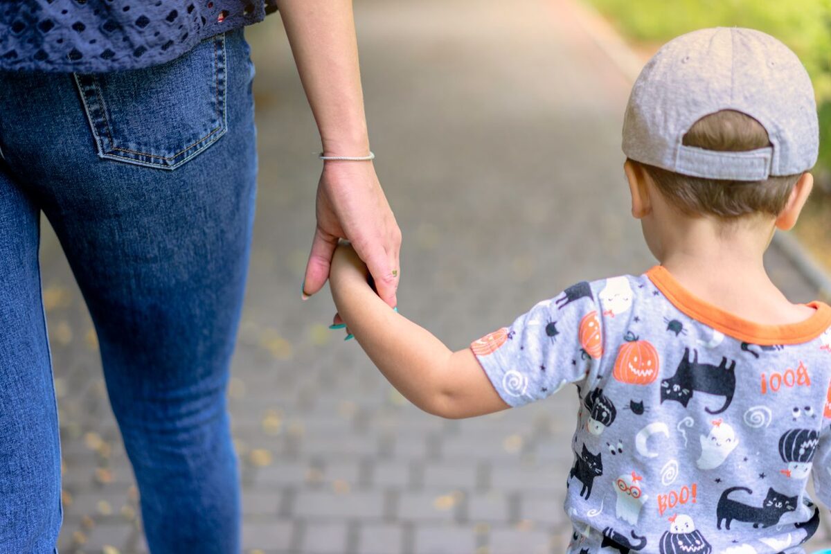 Parent holding a young child's hand while walking - family law custody and visitation documents