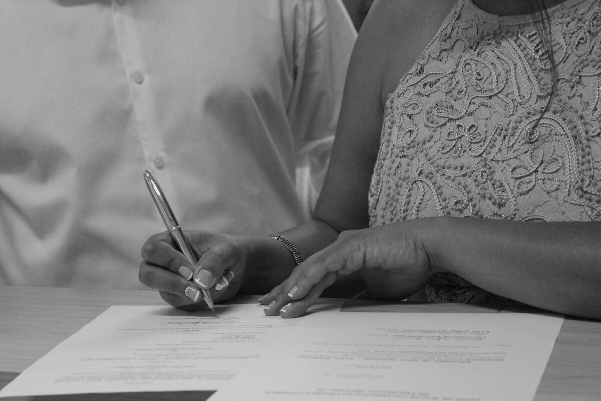 Couple signing an agreement together at a table - prenuptial agreement preparation